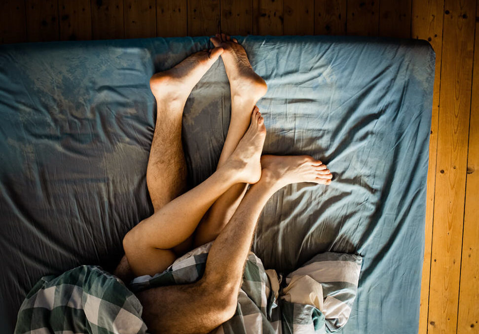 Couple in bed, feet showing from under the blankets